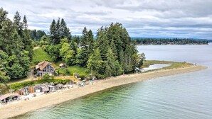 Une zone côtière avec une plage, une maison en bois et une forêt dense.