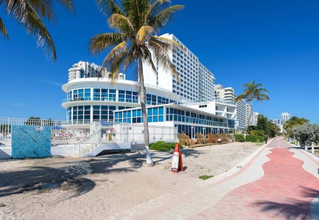 A modern hotel with a curved facade, large windows, and a beachside location.