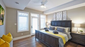 Ein Schlafzimmer mit einem großen Bett, einem Nachttisch, einem Deckenventilator und einem Fenster mit Jalousien.