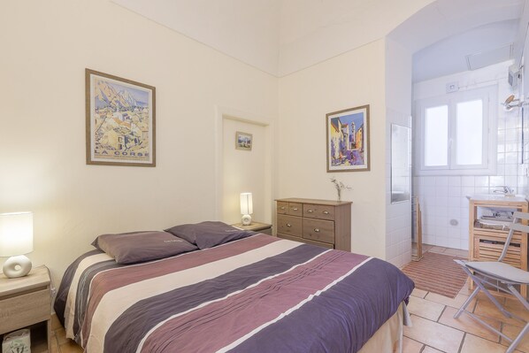Un dormitorio con cama, mesitas de noche, cómoda y obras de arte en las paredes.