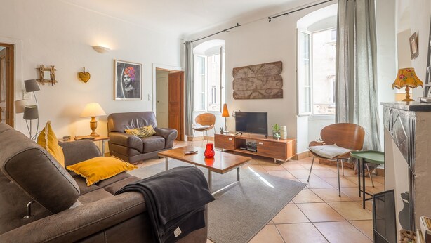 A living room with a sofa, coffee table, TV, and various decorative items. - Le Napoléon - Appt à moins d'un km de la plage (L'Île-Rousse)