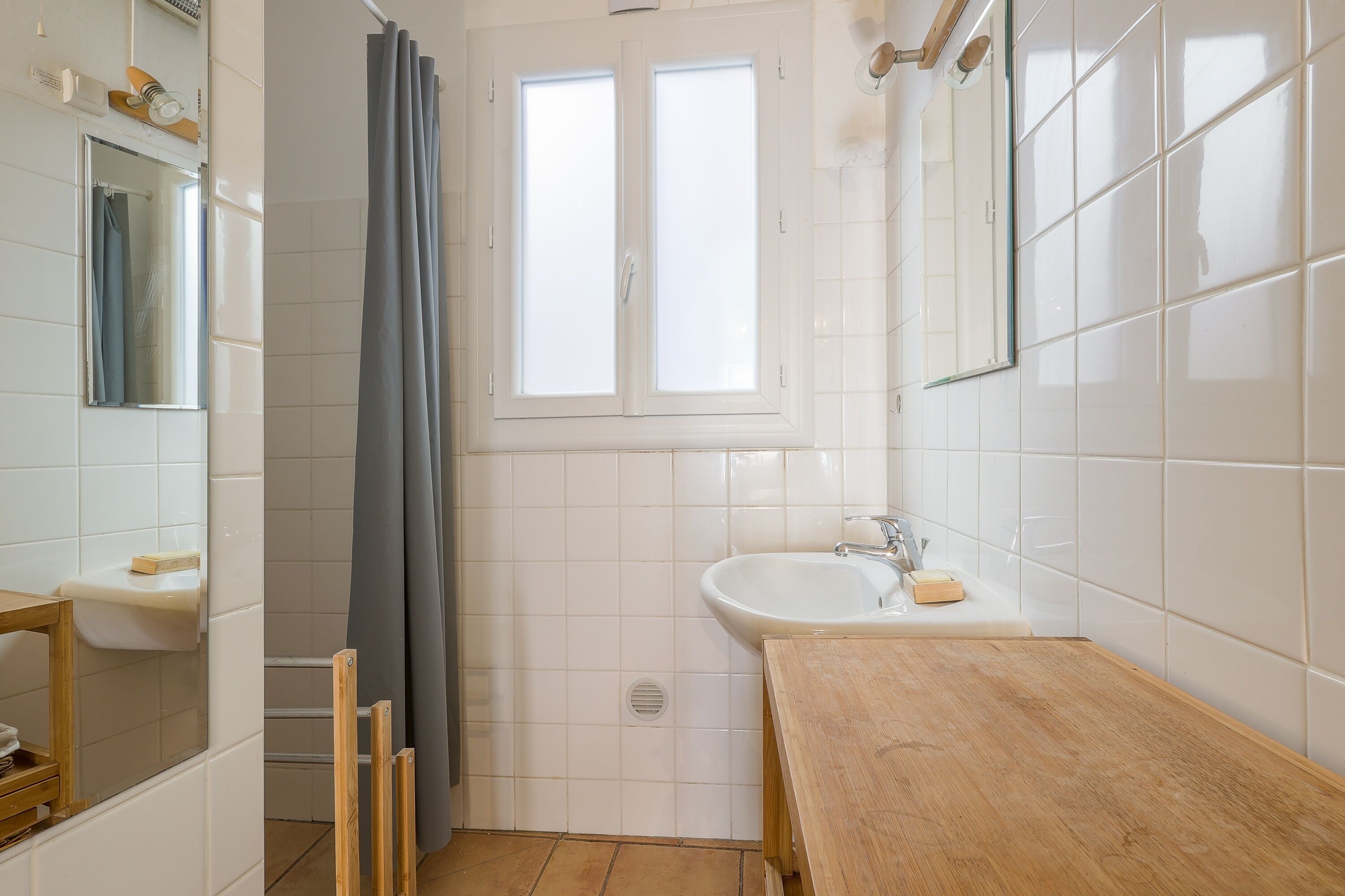 A bathroom with a wooden vanity, a sink, a mirror, and a shower curtain.