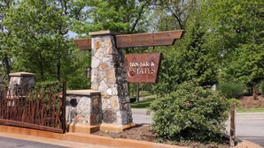 Ein Schild für 'Tan-Tara Estates' mit einer Steinsäule und einem Metallzaun.
