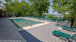 A pool area with green lounge chairs and a view of the lake.