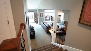 A spacious living area with a staircase leading to an upper floor, a sofa set, and a dining area.