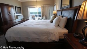 A hotel room with a large bed, a TV, a desk with a lamp, and a balcony with a chair. - Stunning Lake View 4br 5ba (Osage Beach)
