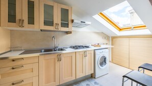 Una cocina moderna con armarios de madera, lavadora integrada y tragaluz.