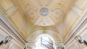 Un salón espacioso con techo alto, molduras elaboradas y un elemento decorativo central.