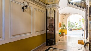 Un pasillo interior con suelo de mosaico, una escalera y vistas al exterior.