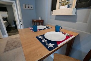 A dining table with two plates, two blue mugs, and a patriotic placemat.