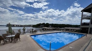 En swimmingpool med utsikt över en vattenyta och ett fartyg i fjärran.