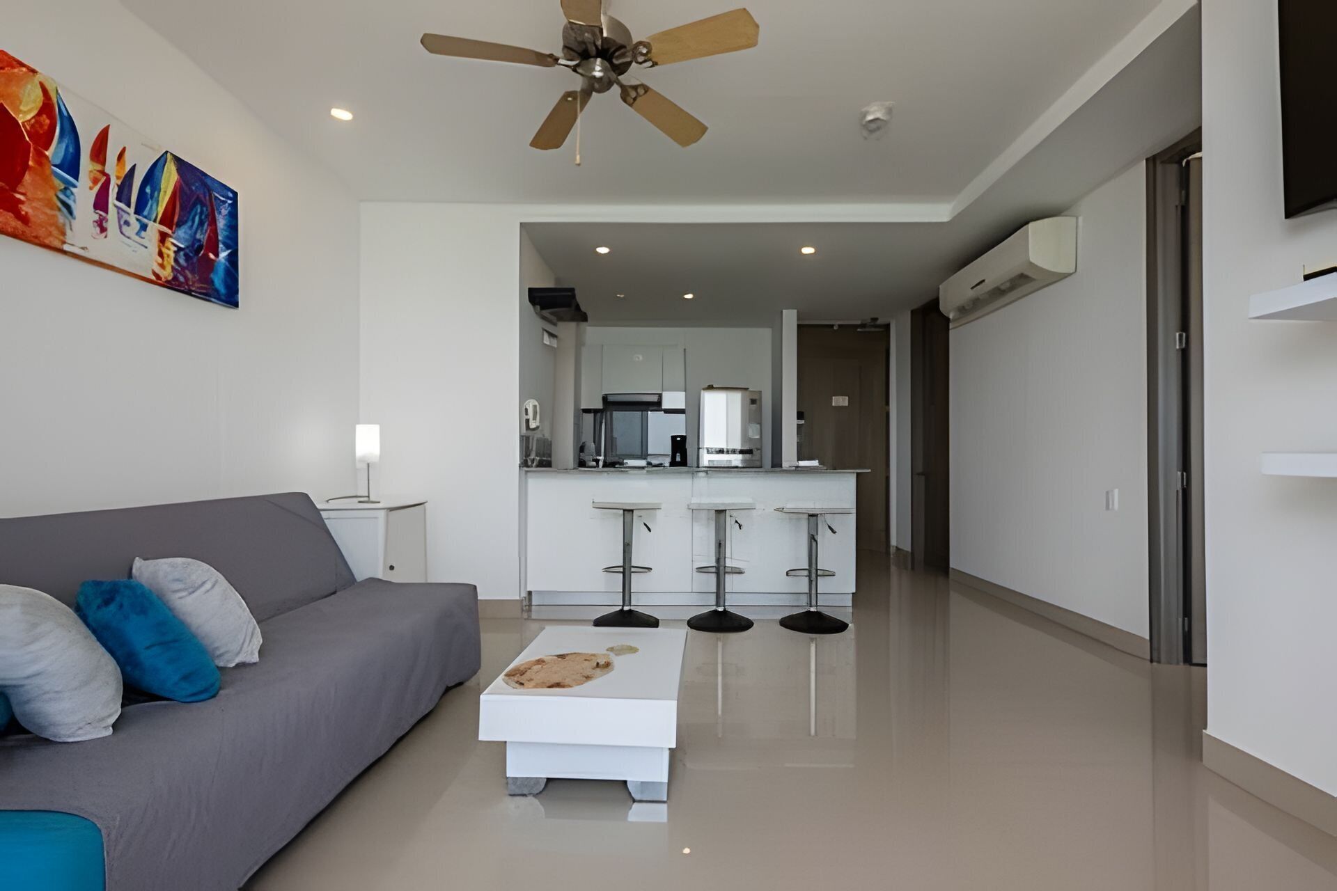 Een moderne woonkamer met een grijze bank, een bijzettafeltje en een plafondventilator.