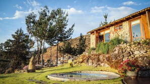 A stone house with a pool, surrounded by a well-maintained lawn and trees. - Refugio Viñak (Vinac)