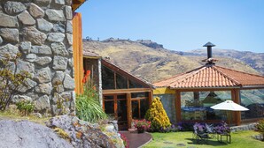 A stone building with a wooden entrance and a glass conservatory with a tiled roof. - Refugio Viñak (Vinac)