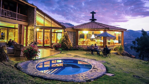 A luxurious outdoor setting with a swimming pool, dining area, and a view of the mountains. - Refugio Viñak (Vinac)