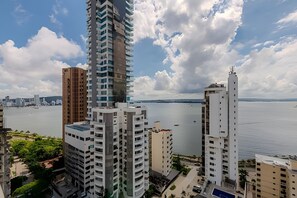Um edifício alto com vários andares, vista para o mar e um céu nublado.