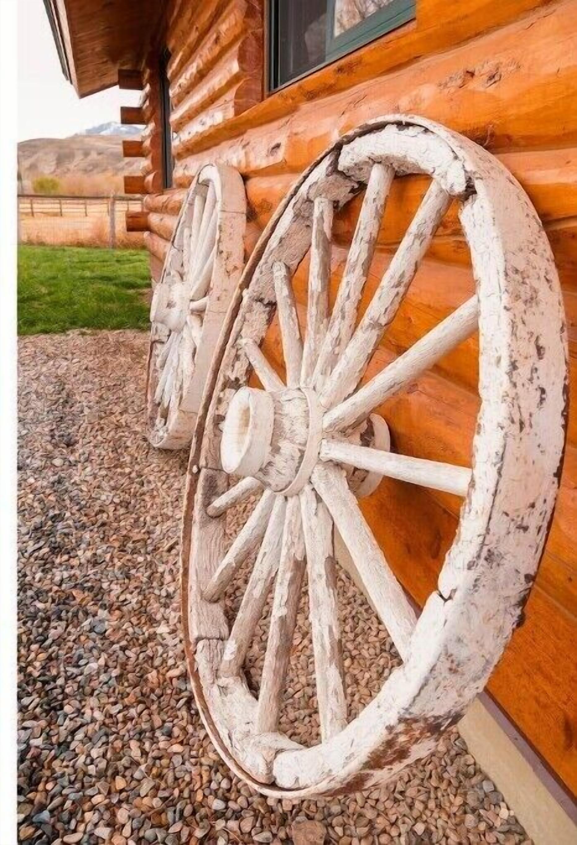 A rustic wooden cabin with large, weathered wooden wheels attached to the exterior wall.
