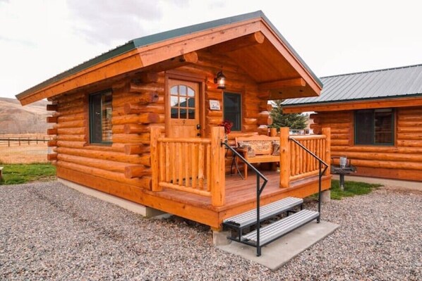 A log cabin with a porch, a table, and a bench.