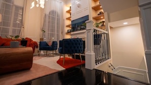 A modern living room with a fireplace, blue chairs, and a red rug. - Luxury Townhome Minutes From DC (Alexandria)