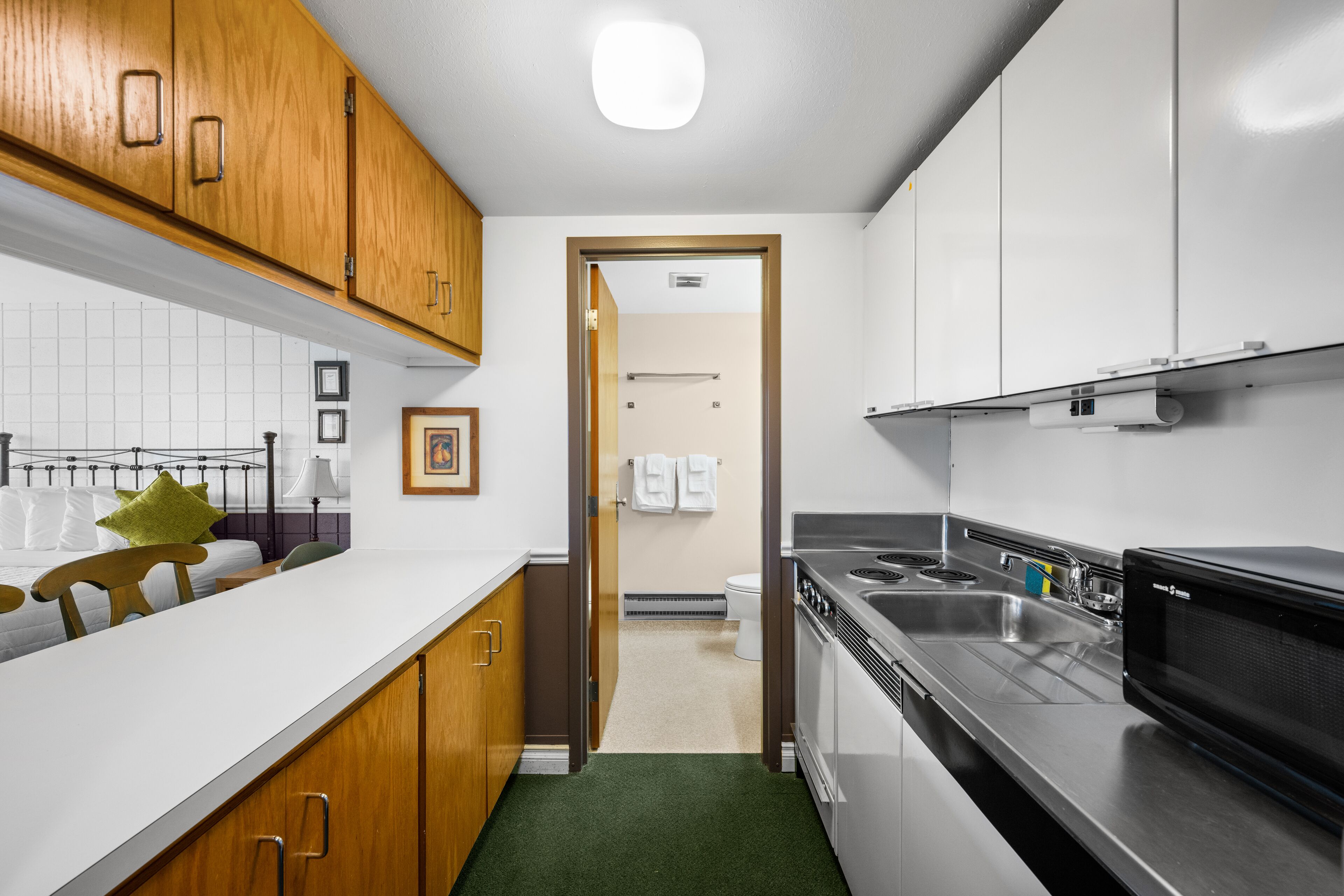 A modern kitchen with wooden cabinets, a stainless steel sink, and a microwave.