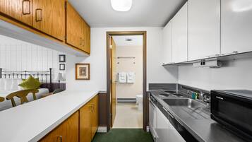 A modern kitchen with wooden cabinets, a stainless steel sink, and a microwave.