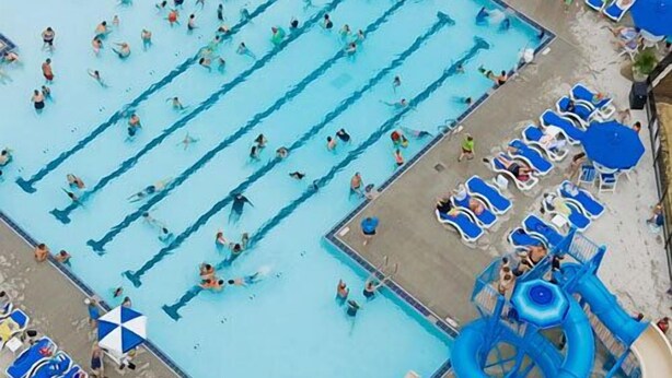 A swimming pool with multiple lanes, a water slide, and lounge chairs around the perimeter. - The Fountain Inn (Marblehead)