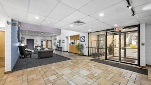 A spacious lobby with a reception desk, seating area, and a glass door entrance. - The Fountain Inn (Marblehead)