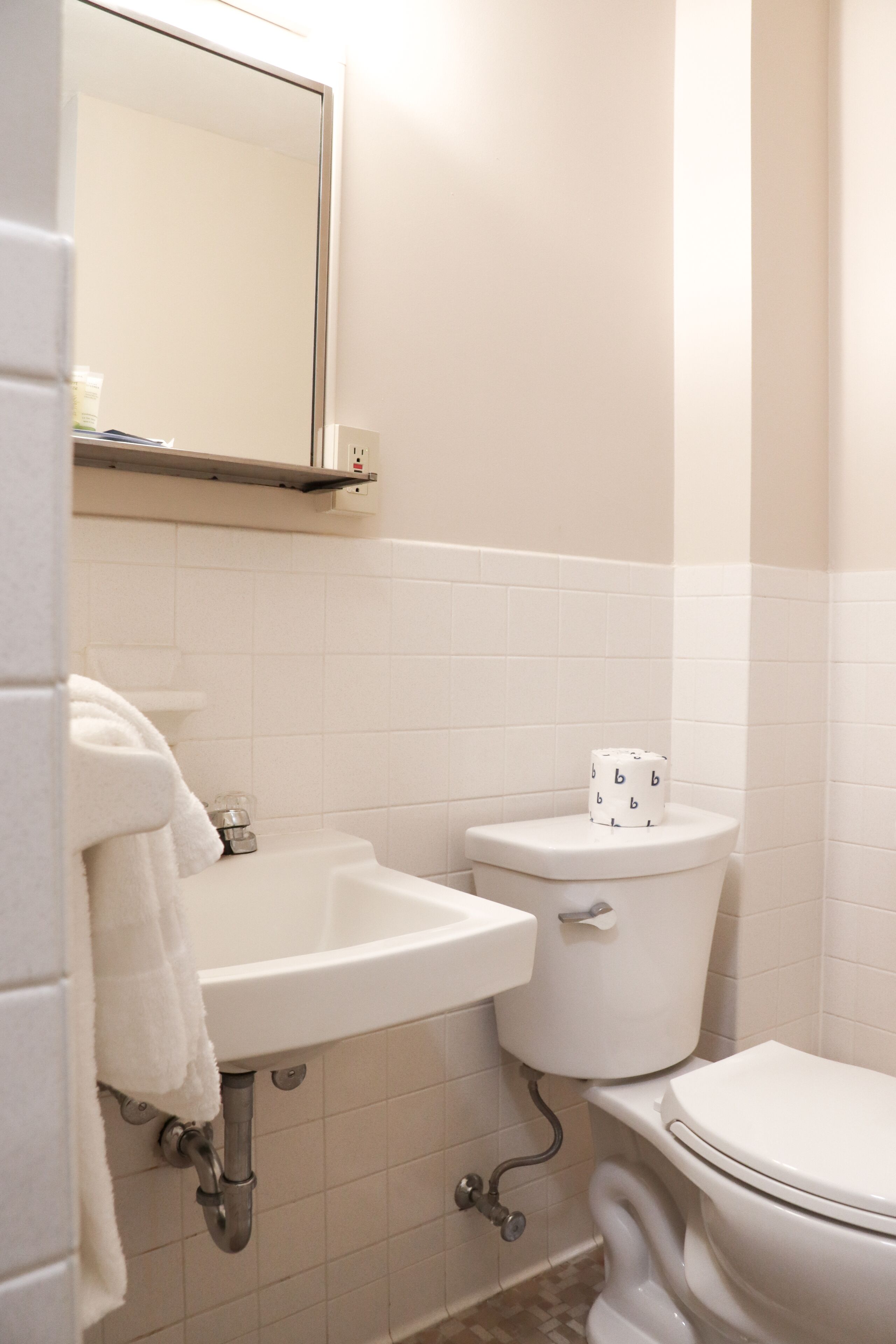 A bathroom with a white sink, toilet, and mirror.