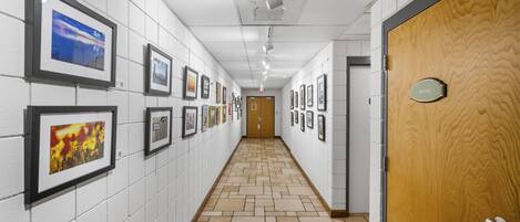 A hallway with framed pictures on the walls, a wooden door labeled "PRIVATE," and a tiled floor.