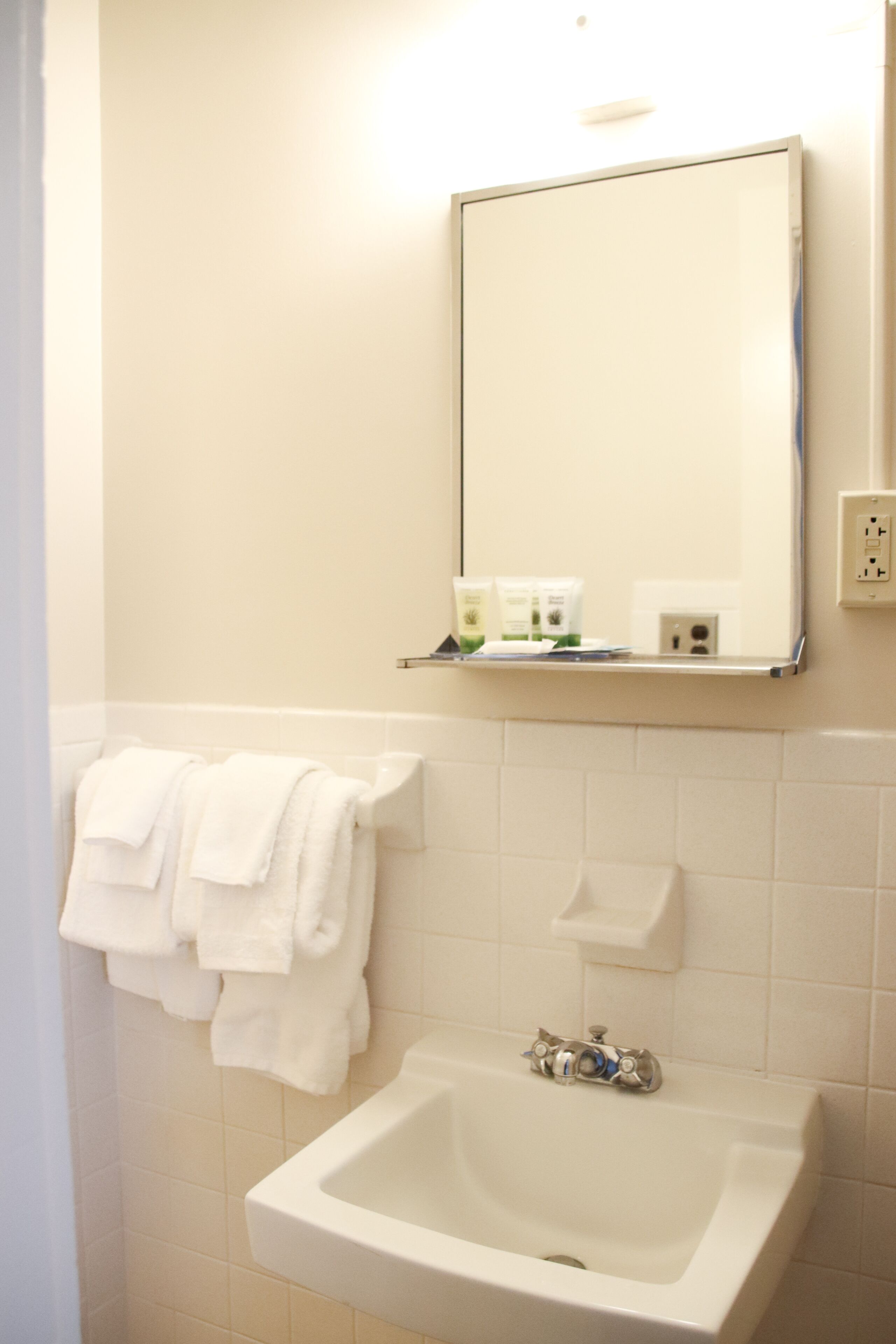 A bathroom with a sink, mirror, and towel rack.