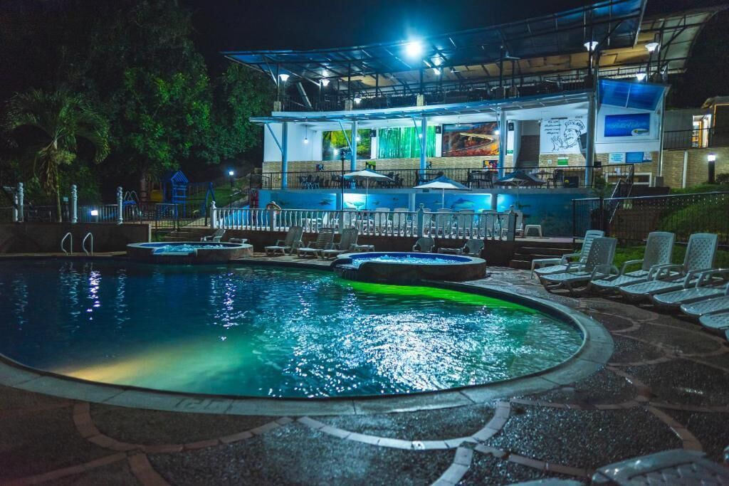 A swimming pool with lounge chairs and a covered area with a bar.