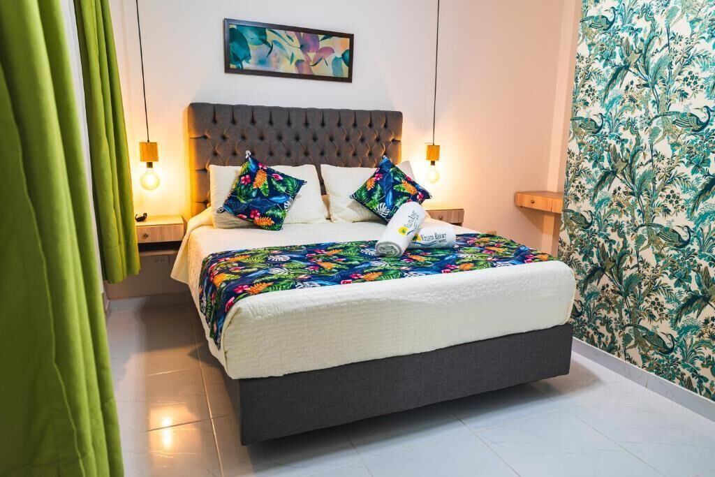 A neatly made bed with a floral bedspread, a tufted headboard, and two bedside lamps.