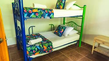 Una cama litera con una colcha estampada, una mesita de madera y un suelo de baldosas.