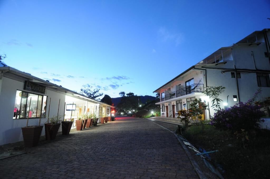 Una calle adoquinada flanqueada por edificios, incluyendo una boutique y un edificio residencial con balcones.