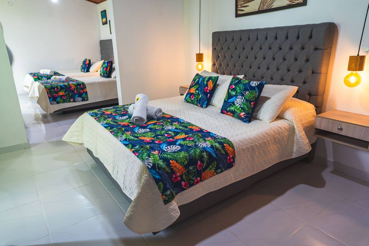 Een tweepersoonsbed met een bloemenprint sprei, een gestapeld hoofdbord en twee bedlampjes.
