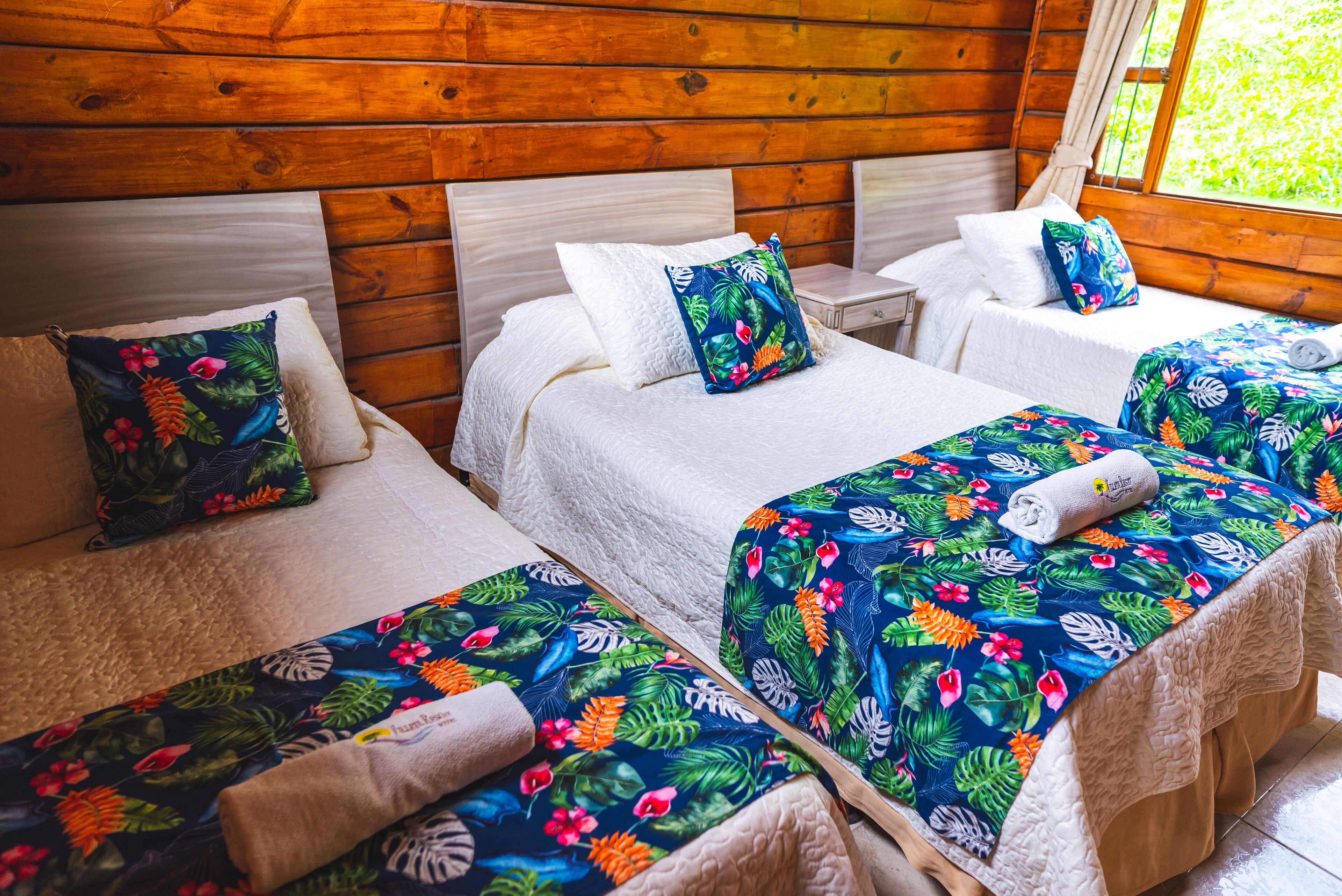 Una habitación con tres camas, cada una con una colcha estampada y ropa de cama blanca.