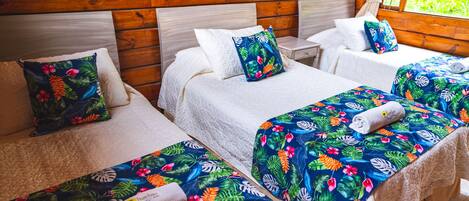 Una habitación con tres camas, cada una con una colcha estampada y ropa de cama blanca.