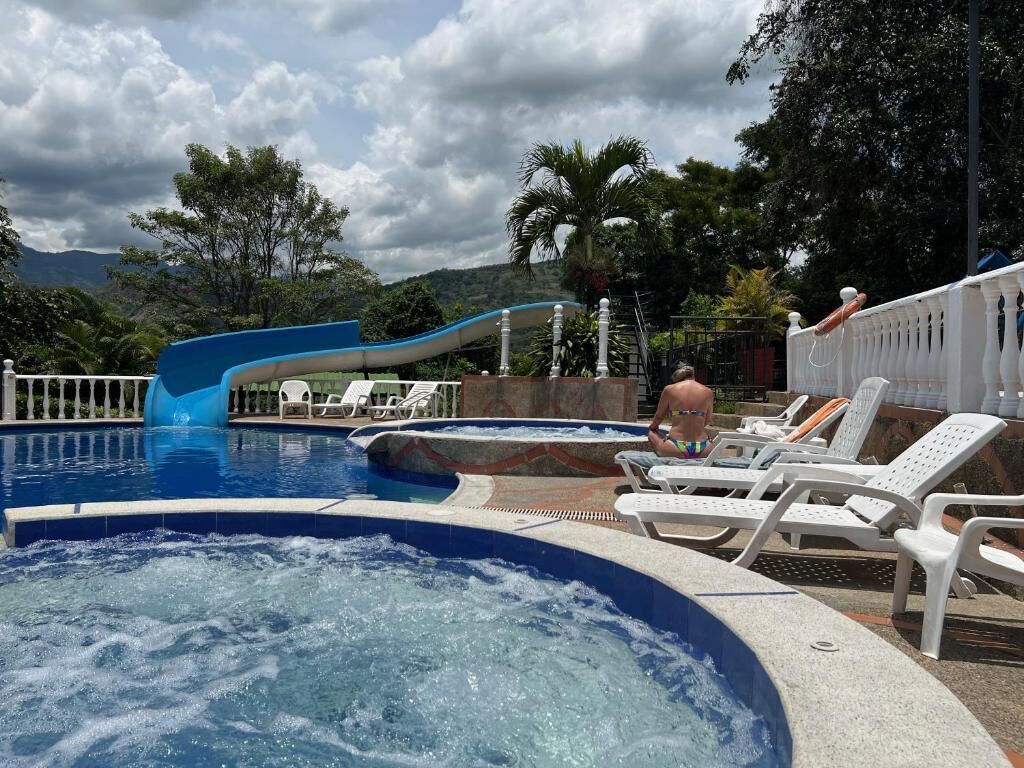Un área de piscina con jacuzzi, sillas de descanso y un tobogán de agua.