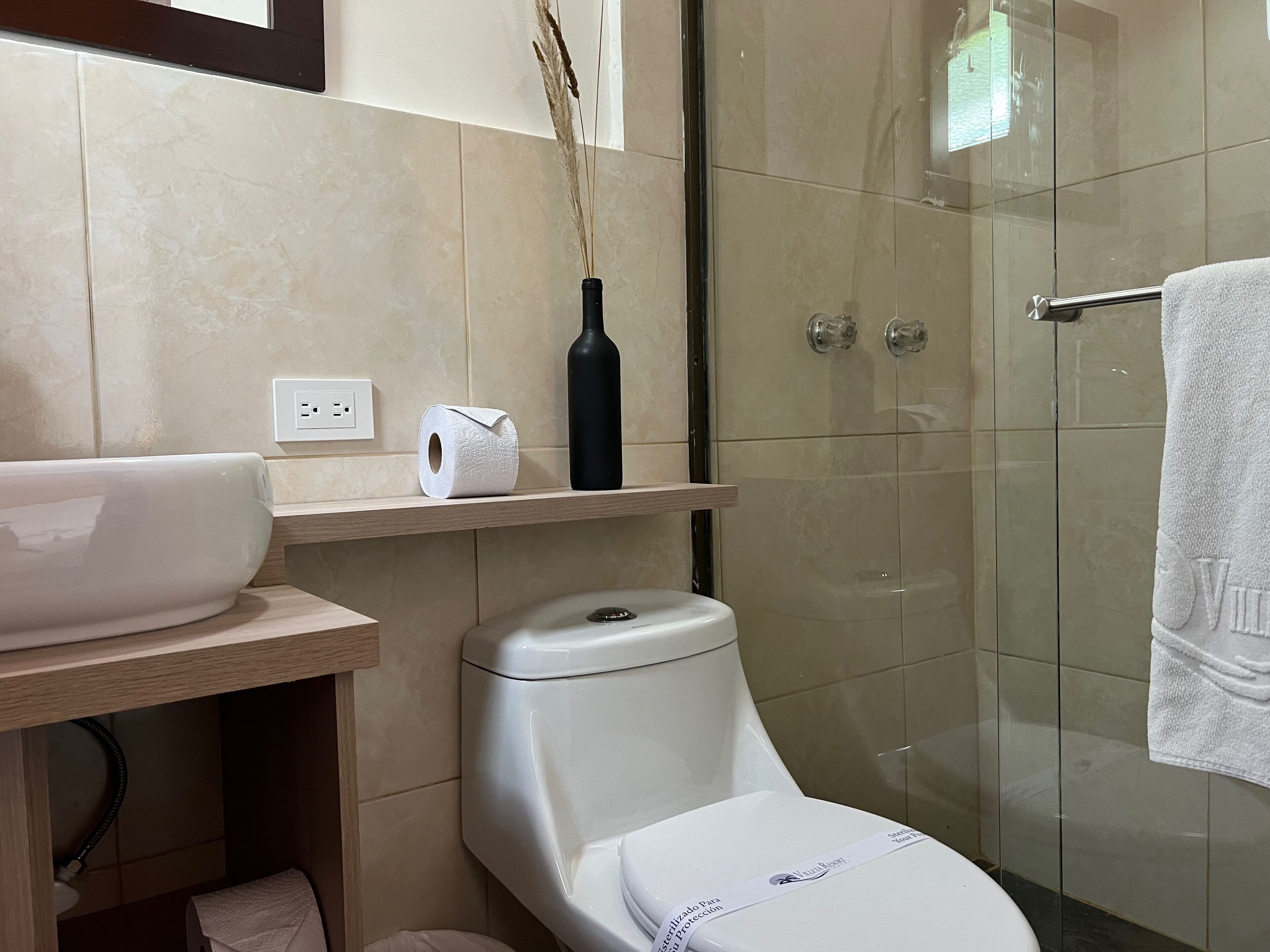 A modern bathroom with a toilet, a sink, and a glass shower enclosure.
