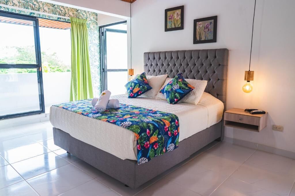 A bedroom with a large bed, a nightstand, and a window with curtains.