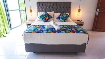 Una cama bien hecha con una colcha floral, dos almohadas decorativas y una toalla doblada al lado.