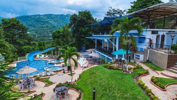 A resort with a pool, lounge chairs, and a view of the mountains. - Villeta Resort Hotel (Villeta)
