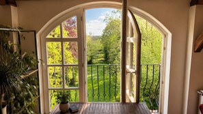 A room with a large arched window, a wooden table, and a potted plant. - Seegut Blaue Blume (Boitzenburger Land)