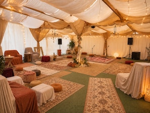 Een evenementenruimte met tenten, tafels, stoelen en een podium.