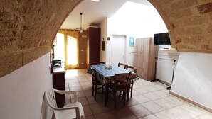 Un coin repas avec une table dressée pour quatre personnes, un buffet en bois et un téléviseur posé sur un meuble.