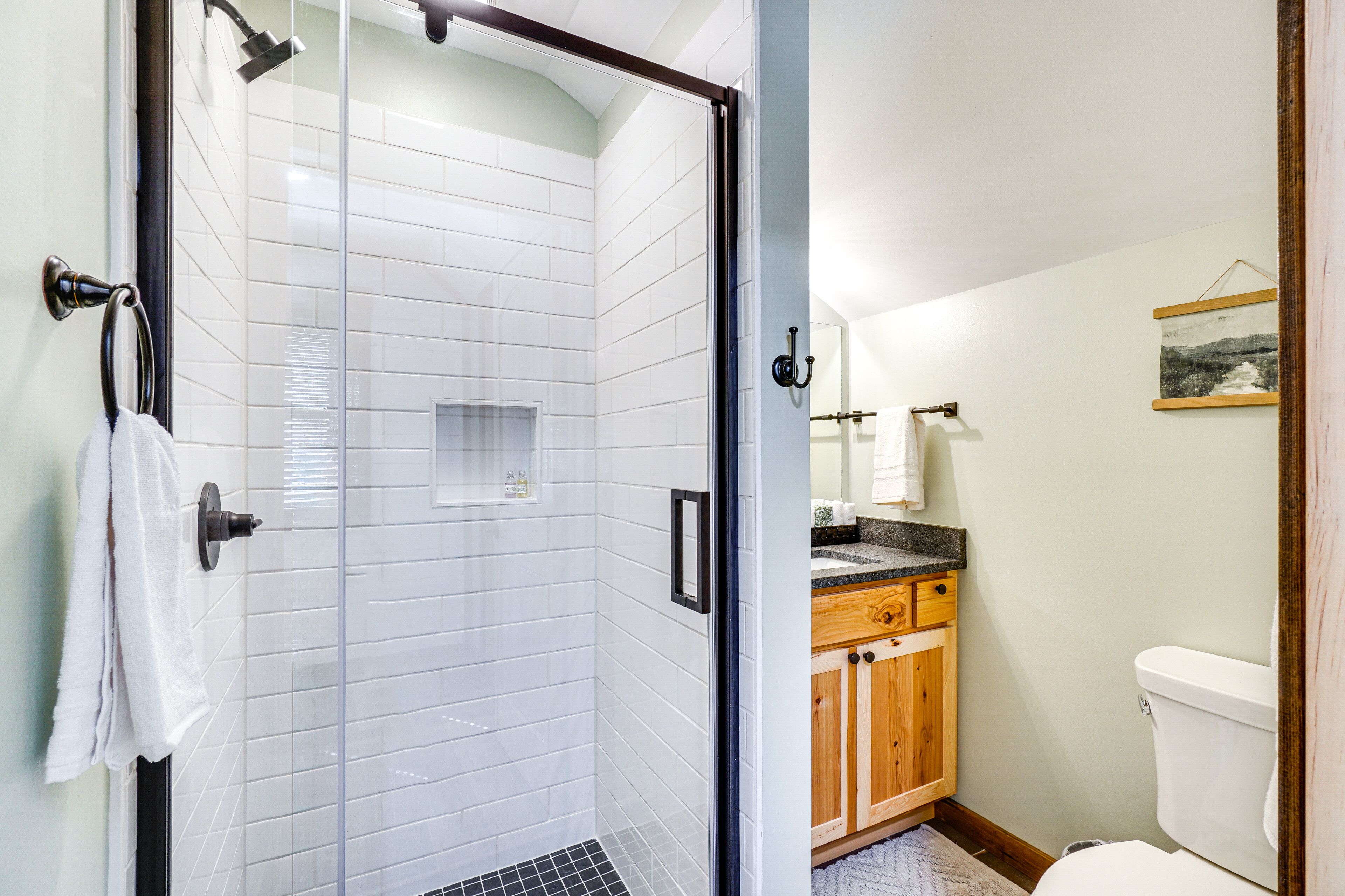 Une salle de bain moderne avec une douche à parois de verre, des meubles en bois et des toilettes blanches.
