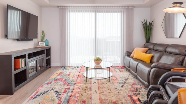 Un salon moderne avec un canapé en cuir, une table basse en verre et un téléviseur fixé au mur.