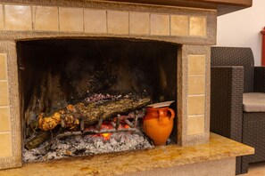 A fireplace with burning logs and a ceramic pot. - Antico Borgo Perrotta (Benevento)