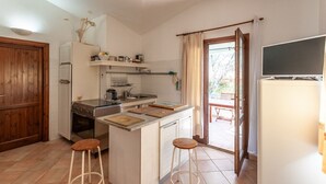 Cocina compacta con isla central, puerta de madera y vista a un patio exterior.