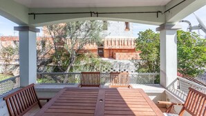 Un espacio de estar al aire libre techado, con vista a un edificio de paredes de ladrillo rojo y fachada blanca.
